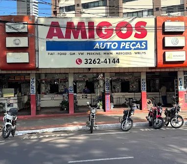Fachada da Amigos Auto Peças, com o letreiro da loja e placas das marcas atendidas.