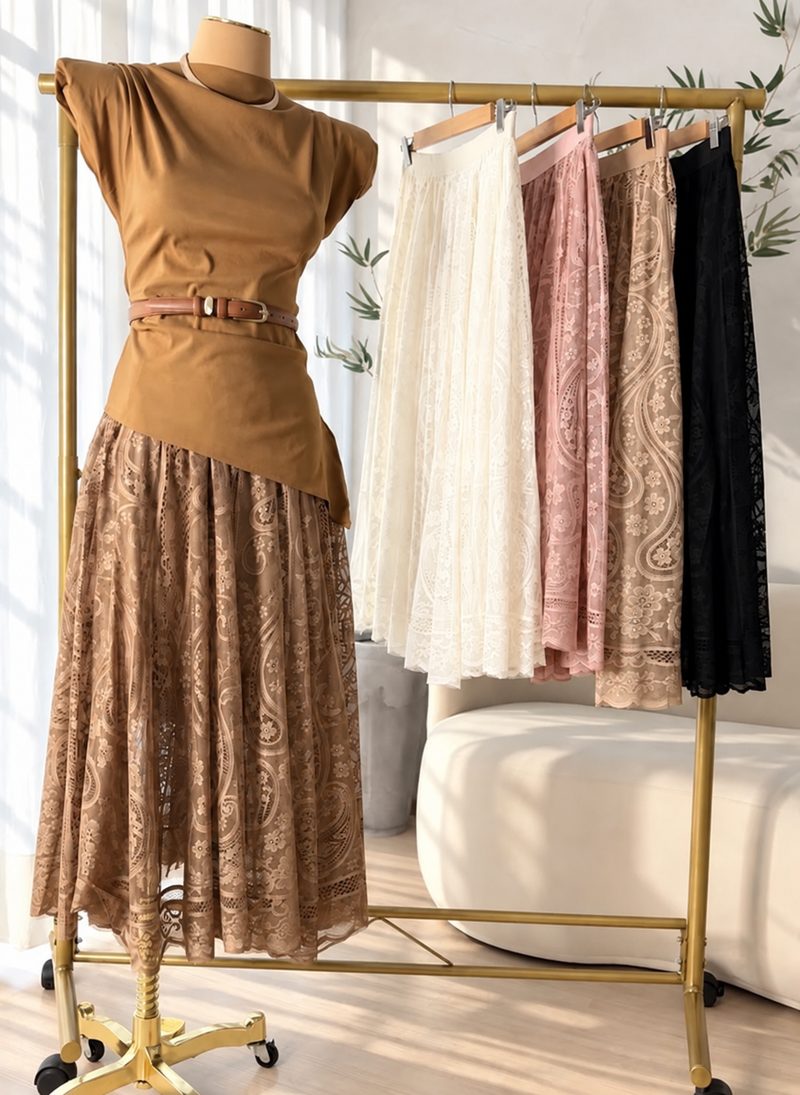 Manequim com blusa caramelo e saia longa de renda marrom, ao lado de uma arara com a saia em off-white, rosé, bege e preto.