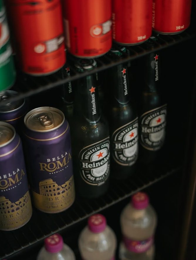 Geladeira da barbearia com cervejas, refrigerantes e água.