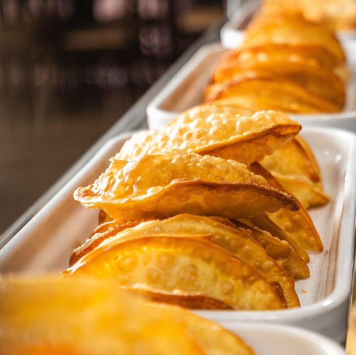 Pastéis fritos arrumados em travessas brancas no buffet.