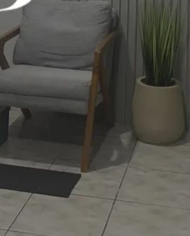 Poltrona cinza e um vaso com planta ao lado da parede ripada da clínica.
